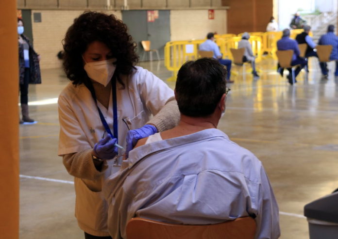 Una infermera vacuna un veí de Sant Boi de Llobregat de 65 anys en el dia en què es reprèn la vacunació amb AstraZeneca i s'hi incorpora la població de 60 a 65 anys, al poliesportiu L'Olivera. 24 de març del 2021. (Horitzontal)