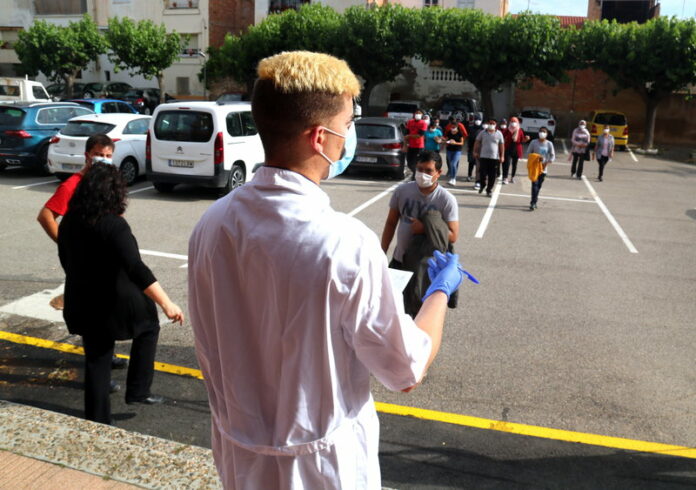 Pla escorç d'un sanitari cridant els treballadors de la fruita dolça citats per vacunar-se local de la Democràcia de Móra d'Ebre. Imatge del 3 de juny de 2021. (Horitzontal)